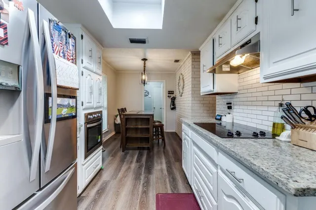 a kitchen with granite countertop a sink a counter space stainless steel appliances and cabinets