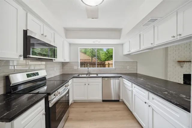a kitchen with stainless steel appliances granite countertop white cabinets granite counter tops and a window