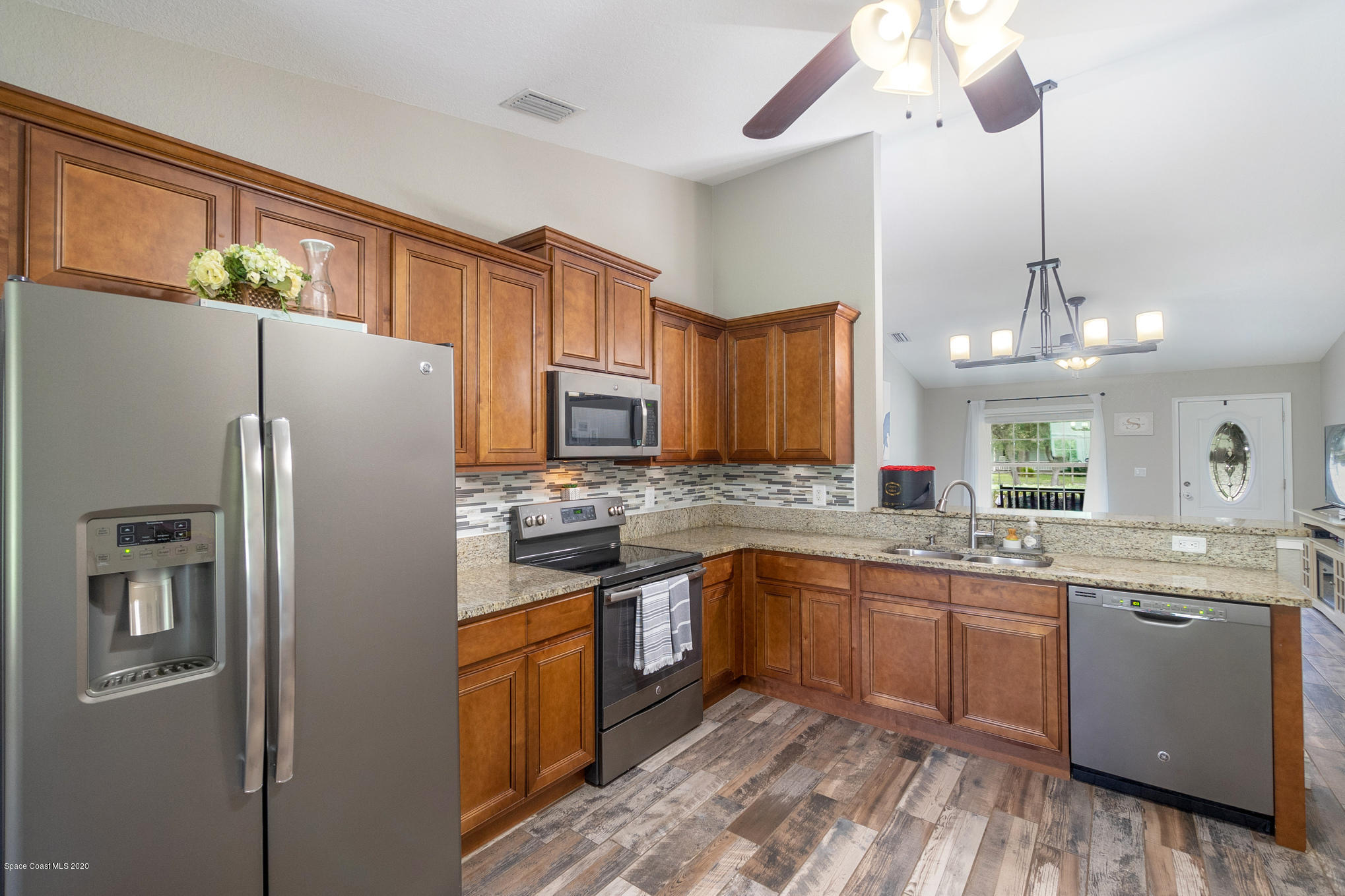 3452 Brevard Road Mims, FL 32754 - Photo 7 of 23 a kitchen with stainless steel appliances granite countertop a refrigerator a sink dishwasher a stove with white cabinets and wooden floor