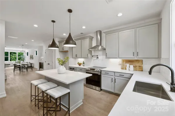 a kitchen with stainless steel appliances granite countertop a stove a sink a oven a dining table and chairs with wooden floor