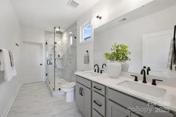 a spacious bathroom with a double vanity sink toilet mirror and shower