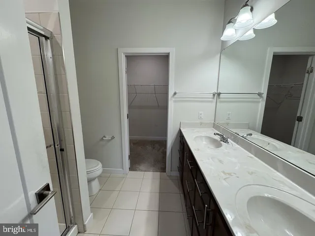 a spacious bathroom with a granite countertop sink a toilet a mirror and shower