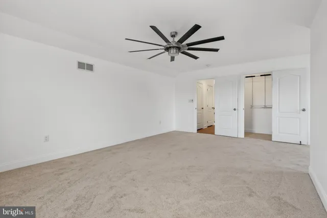 a view of an empty room with wooden floor and closet
