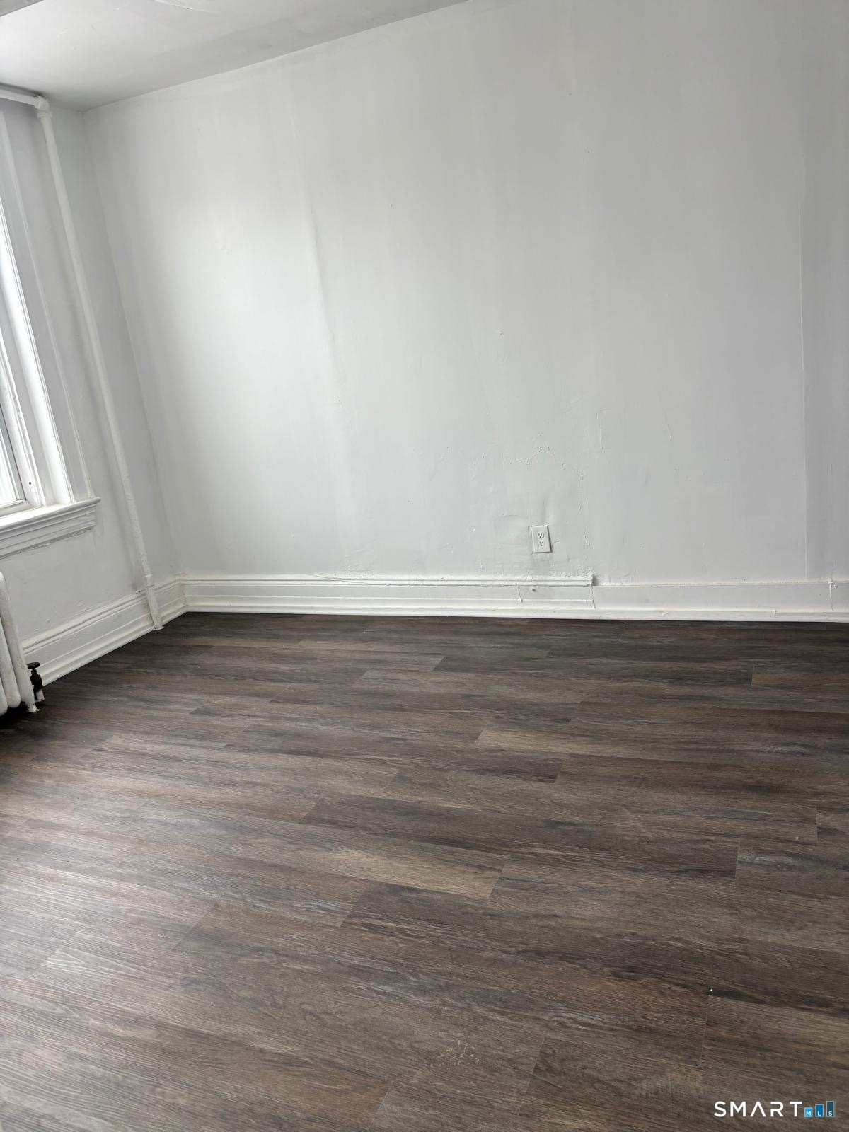 86 Pequonnock Street, Unit 3 Bridgeport, CT 06604 - Photo 2 of 4 a view of an empty room with wooden floor and a window