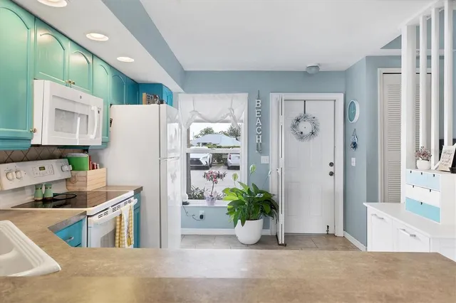 a kitchen with stainless steel appliances a refrigerator a sink a stove and white cabinets