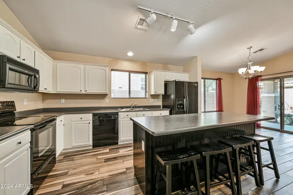 a kitchen with stainless steel appliances granite countertop a stove a sink dishwasher a refrigerator white cabinets and wooden floor