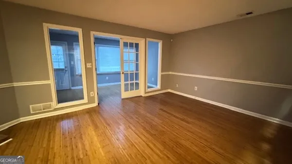 an empty room with wooden floor and windows