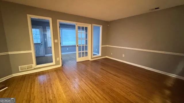 an empty room with wooden floor and windows