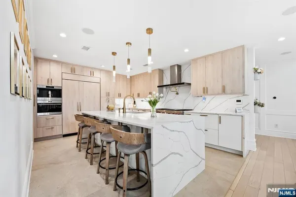 a kitchen with stainless steel appliances kitchen island a stove a sink a refrigerator and chairs