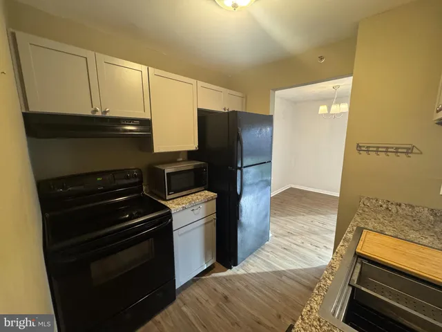 a kitchen with granite countertop a sink a stove cabinets and wooden floor