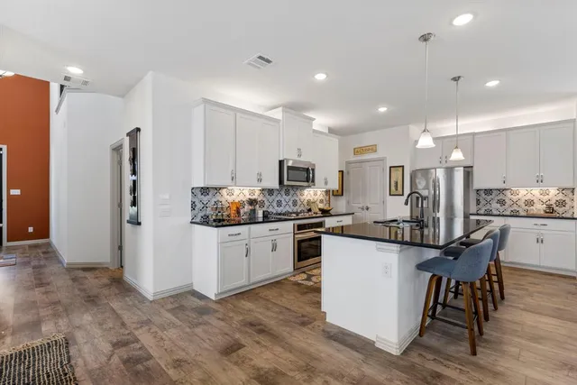 a kitchen with stainless steel appliances kitchen island granite countertop a refrigerator and a stove top oven