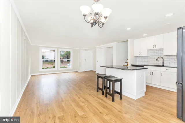 a kitchen with stainless steel appliances granite countertop a stove top oven a sink dishwasher and white cabinets with wooden floor