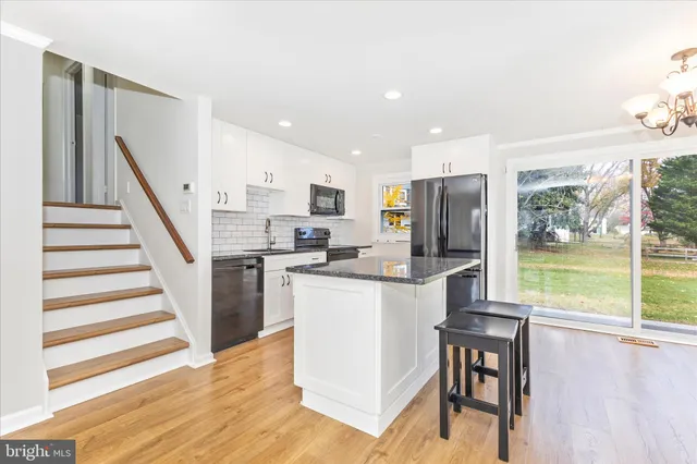 a kitchen with stainless steel appliances granite countertop a refrigerator a stove a sink a oven with white cabinets and wooden floor