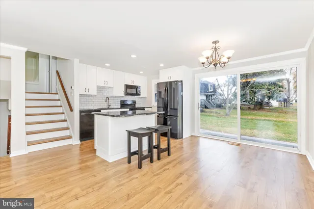 a dining hall with stainless steel appliances kitchen island granite countertop a refrigerator a stove a microwave oven with a dining table and chairs