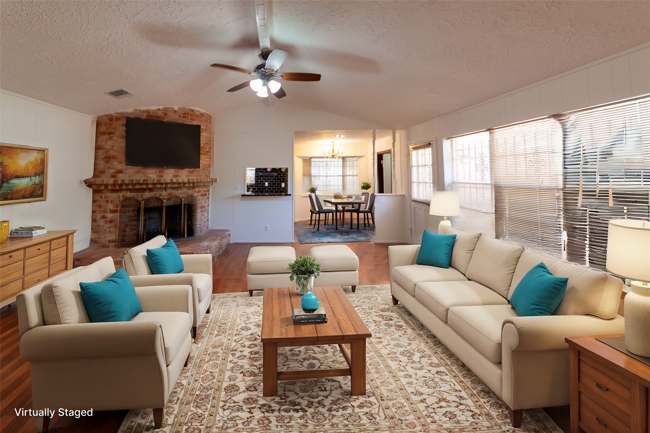 8826 Roos Road Houston, TX 77036 - Photo 4 of 42 This virtually staged living room features a cozy brick fireplace, large windows with blinds for natural light, and a ceiling fan. The space is decorated with neutral-toned furniture accented by blue throw pillows, creating a welcoming and comfortable atmosphere.