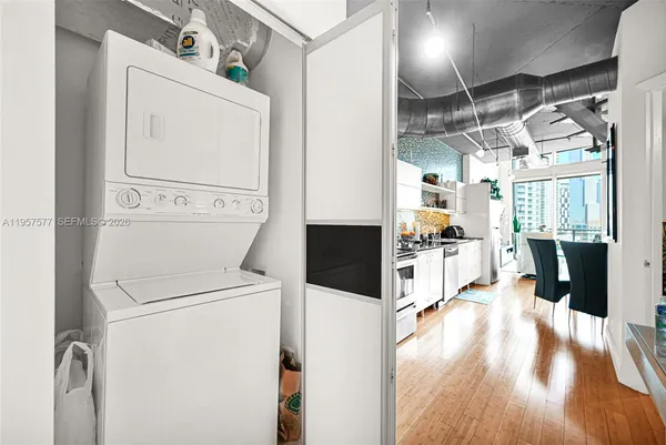 a kitchen with stainless steel appliances granite countertop a stove a sink dishwasher and white cabinets with wooden floor