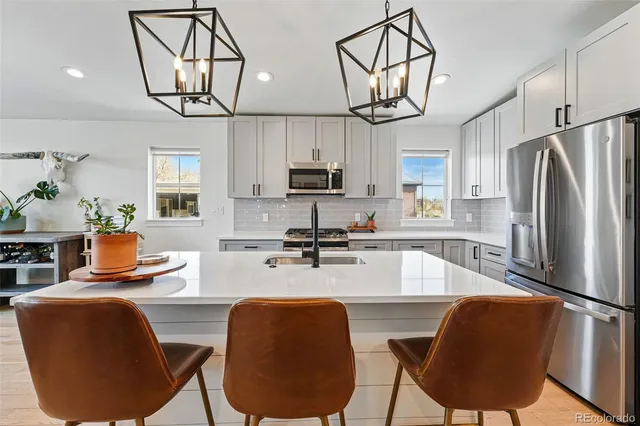 a kitchen with stainless steel appliances granite countertop a refrigerator a sink dishwasher a dining table and chairs with wooden floor