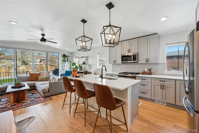 a open kitchen with stainless steel appliances granite countertop a stove a sink dishwasher a dining table and chairs with wooden floor