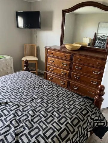 a bedroom with a bed a mirror on dresser and a flat screen tv