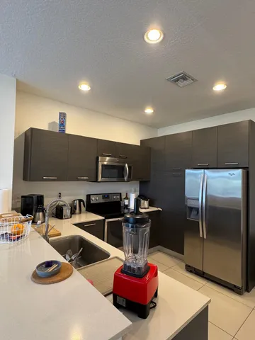 a kitchen with sink a refrigerator and chairs