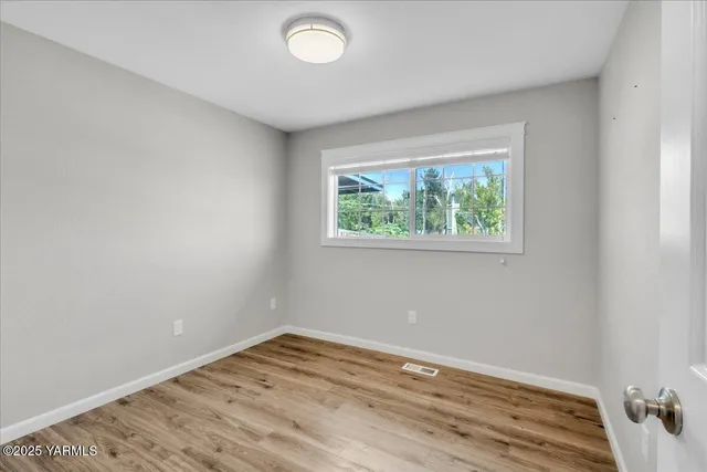 an empty room with wooden floor and window