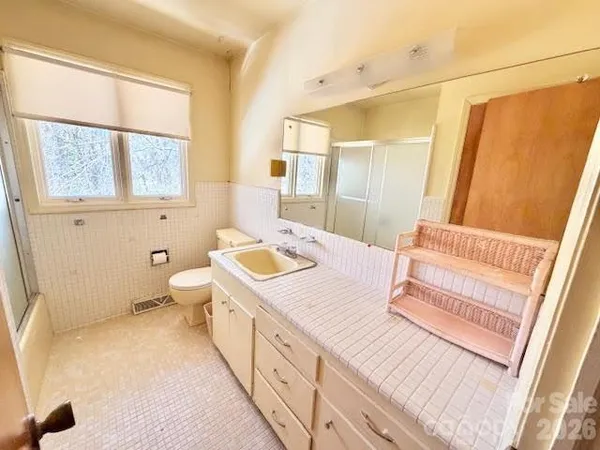 a spacious bathroom with a granite countertop sink a mirror and a toilet