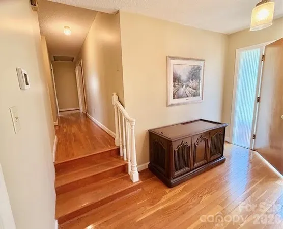 a view of a hallway with wooden floor and staircase