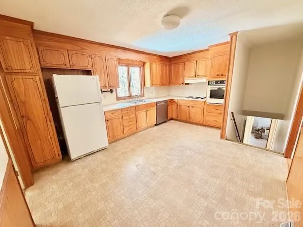 a large white kitchen with sink a refrigerator a oven and a stove with white countertops