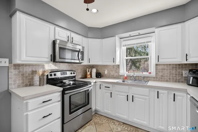 a kitchen with granite countertop white cabinets sink and stainless steel appliances