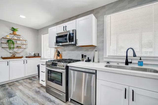 a kitchen with stainless steel appliances granite countertop a sink a stove a microwave and cabinets