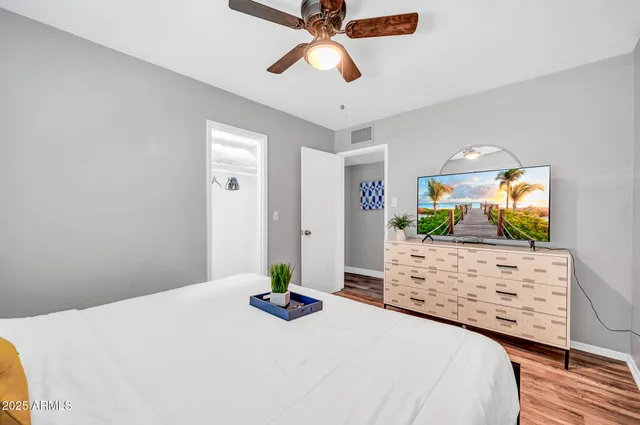 a bedroom with a bed potted plant on the dresser and a chandelier