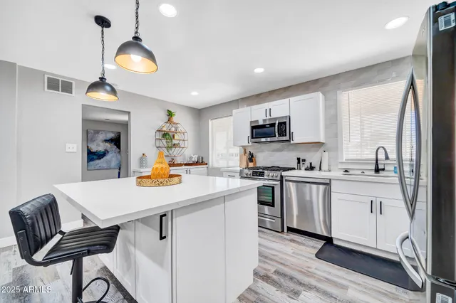 a kitchen with stainless steel appliances granite countertop a stove top oven a sink dishwasher and white cabinets with wooden floor