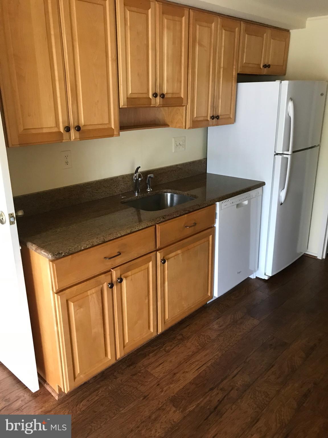 2817 Jermantown Road, Unit 203 Oakton, VA 22124 - Photo 5 of 22 a kitchen with granite countertop white cabinets and refrigerator
