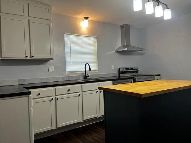a kitchen with stainless steel appliances granite countertop a sink a stove and a wooden cabinets