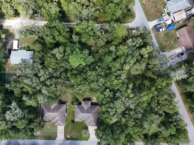 an aerial view of residential house with outdoor space and trees all around
