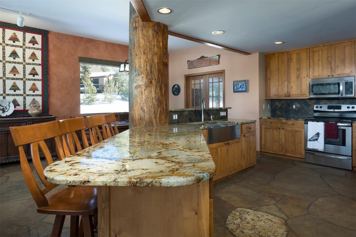 145 F Road Silverthorne, CO 80498 - Photo 6 of 35 a kitchen with kitchen island granite countertop a stove a sink a microwave a dining table and chairs
