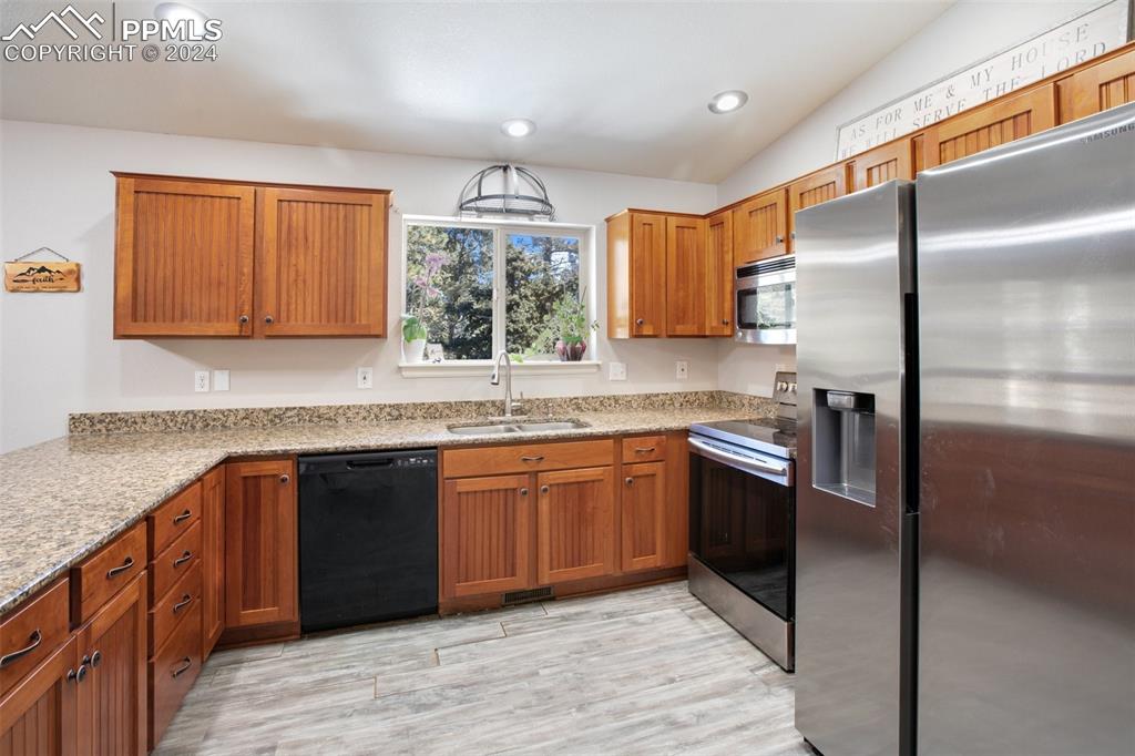 833 Spring Valley Drive Divide, CO 80814 - Photo 18 of 50 a kitchen with stainless steel appliances granite countertop a refrigerator a sink a stove with wooden cabinets and wooden floor