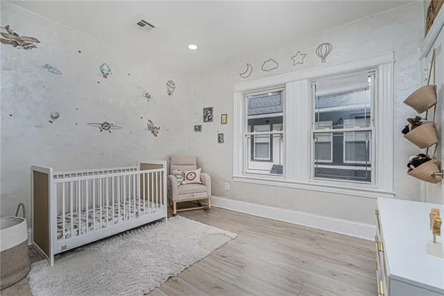 a view of a bedroom with wooden floor & windows