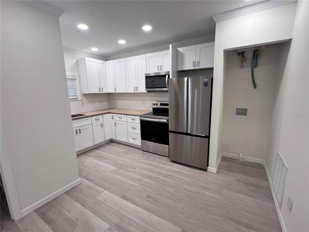 1156 Orange Avenue, Unit A B C D Dunedin, FL 34698 - Photo 3 of 7 a kitchen with stainless steel appliances granite countertop a refrigerator and a stove top oven
