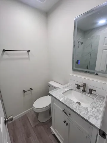 a bathroom with a granite countertop sink a toilet and a mirror
