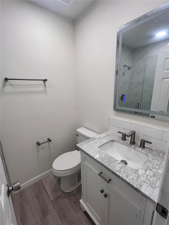 1156 Orange Avenue, Unit A B C D Dunedin, FL 34698 - Photo 4 of 7 a bathroom with a granite countertop sink a toilet and a mirror