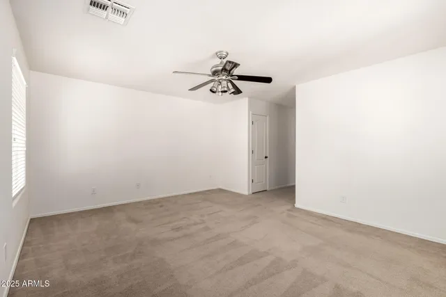 an empty room with a window and a ceiling fan