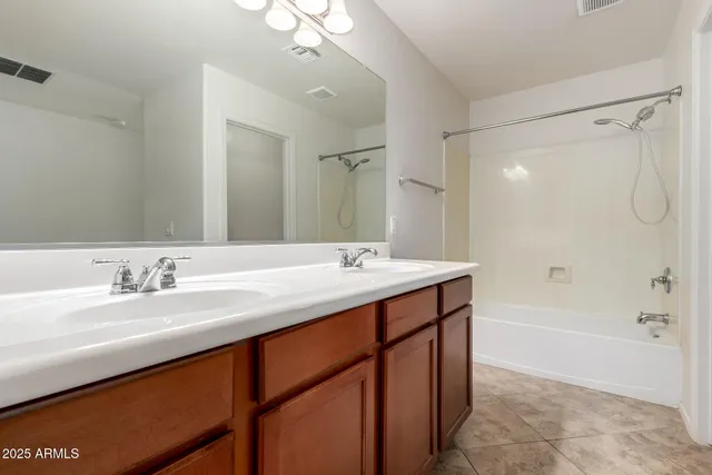 a bathroom with a sink double vanity granite tub shower and a mirror