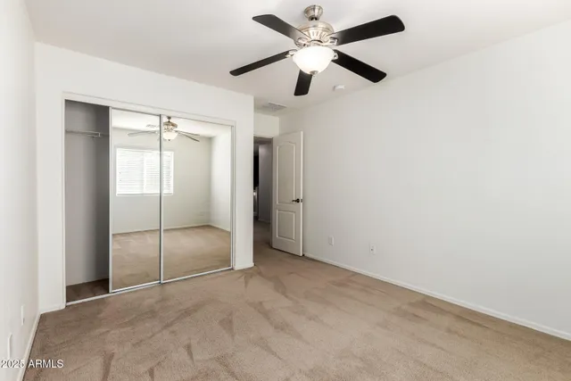 an empty room with closet and a ceiling fan