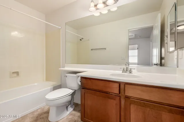 a bathroom with a granite countertop sink a toilet mirror and shower
