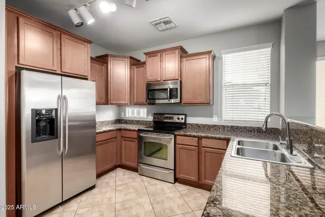 a kitchen with stainless steel appliances granite countertop a refrigerator and a sink