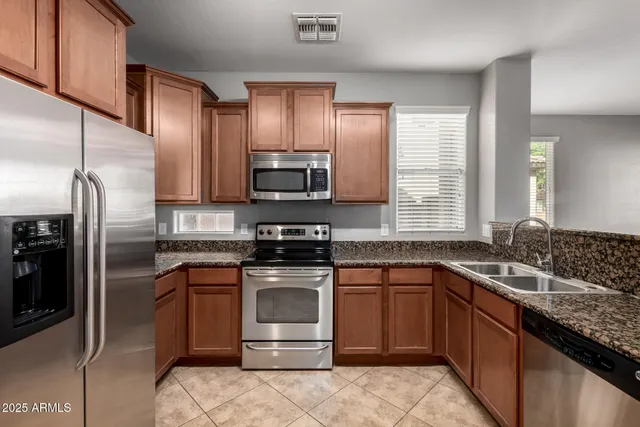 a kitchen with stainless steel appliances granite countertop a sink stove microwave and refrigerator