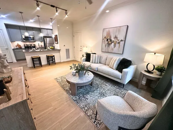 a living room with furniture kitchen view and a chandelier