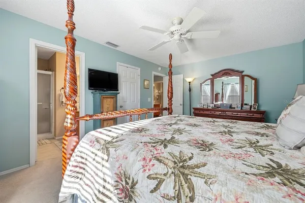 a bedroom with a bed a flat screen tv and a chandelier