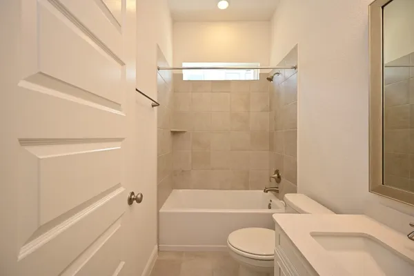 a bathroom with a granite countertop bathtub shower sink vanity mirror and toilet